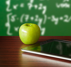 a green apple and a tablet sitting on a desk